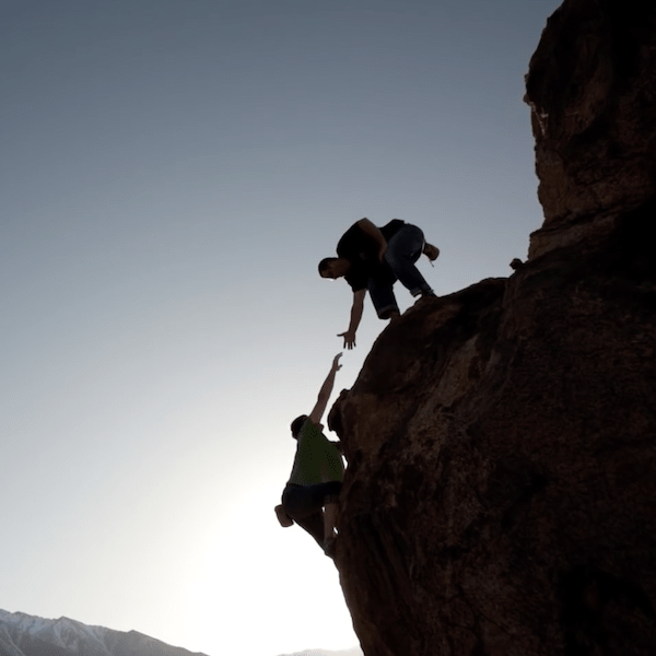 climber helping other climber up rock face